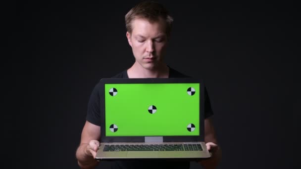 Молодий красивий чоловік використовує ноутбук з зеленим екраном хром ключ — стокове відео