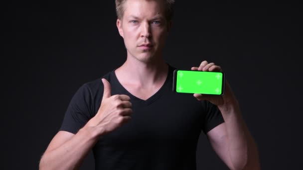 Jonge knappe man met behulp van mobiele telefoon met Chromakey, key groen scherm — Stockvideo