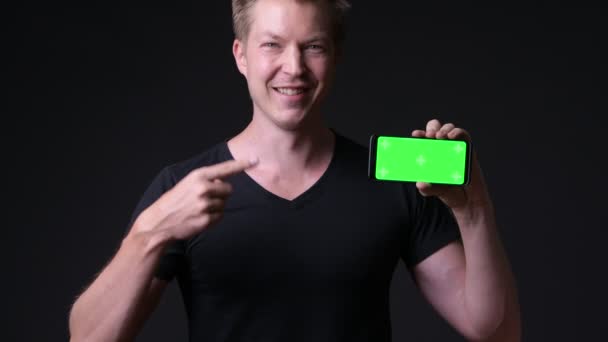 Молодой красивый мужчина использует мобильный телефон с зеленым экраном хрома ключ — стоковое видео