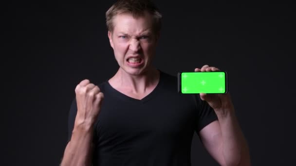 Jonge knappe man met behulp van mobiele telefoon met Chromakey, key groen scherm — Stockvideo