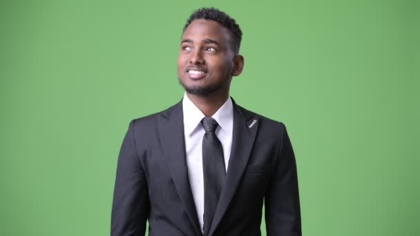Mladý pohledný africký podnikatel proti zeleným pozadím — Stock video