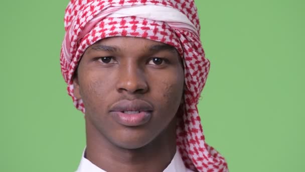 Young African man wearing traditional Muslim clothes against green background — Stock Video