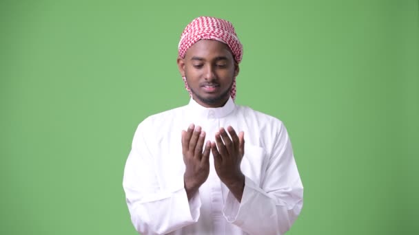 Young handsome African man wearing traditional Muslim clothes against green background — Stock Video