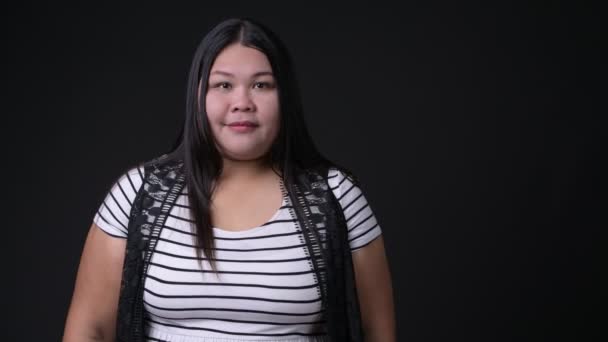 Vackra överviktiga asiatisk kvinna mot svart bakgrund — Stockvideo