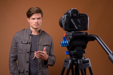 Stüdyo çekimlerinde, genç ve yakışıklı bir adam kamerayla video kaydediyor.