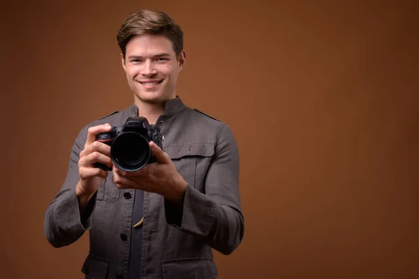 Studioaufnahme eines jungen gutaussehenden Mannes als Fotograf mit Kamera — Stockfoto