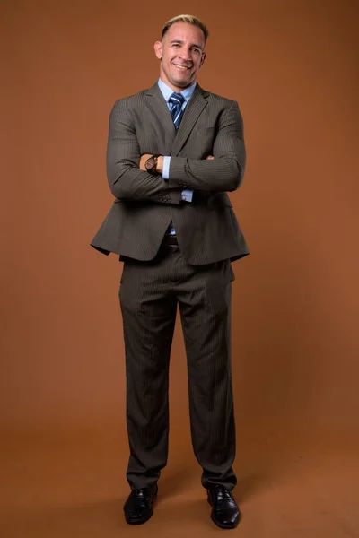 Cuerpo completo de hombre de negocios de pie sobre fondo marrón —  Fotos de Stock