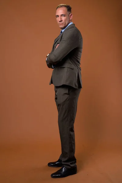 Повний знімок тіла бізнесмена, що стоїть на коричневому фоні — стокове фото
