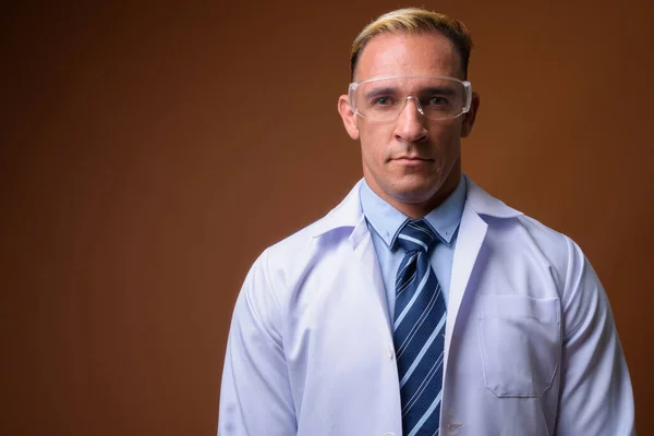 Férfi orvos, védő szemüveg, barna háttér — Stock Fotó