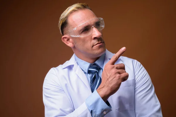 Férfi orvos visel védő szemüveg, miközben gondolkodás — Stock Fotó
