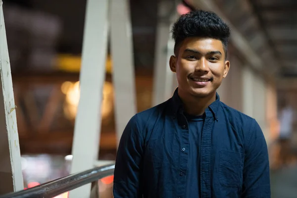 Gezicht van gelukkig jong aziatisch man glimlachen op de voetgangersbrug 's nachts — Stockfoto
