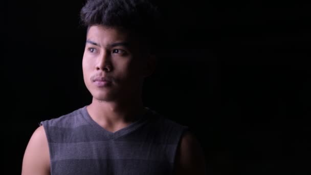 Mladý asijský muž myšlení při pohledu pryč na noc venku — Stock video