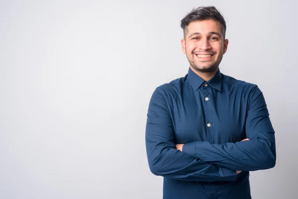 Kollarını kavuşturup gülümseyen mutlu genç İranlı işadamının portresi.