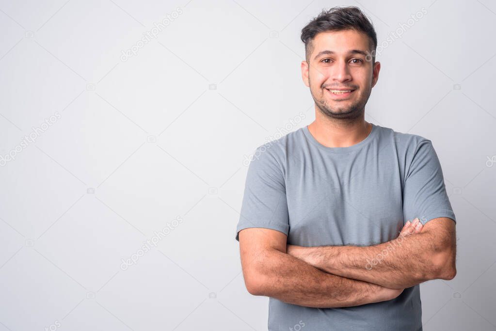 Portrait of happy young Persian man smiling with arms crossed