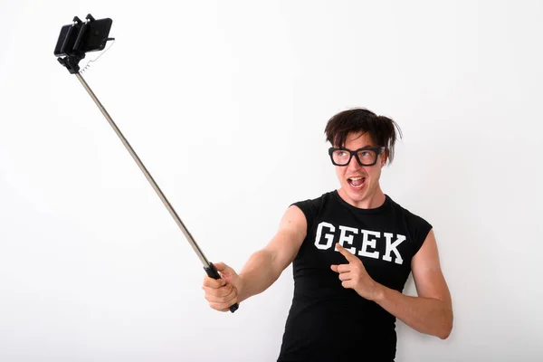 Hombre nerd tomando fotos con el teléfono móvil conectado al palo de selfie — Foto de Stock