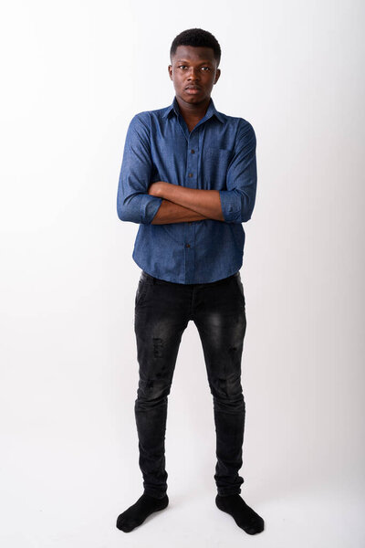 Full body shot of young black African man standing with arms crossed against white background