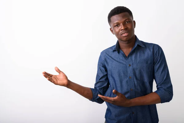 Studio shot of young black African man showing something against — Stock Photo, Image
