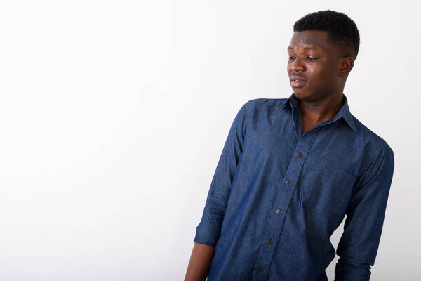 Studio shot of young black African man thinking while looking disgusted against white background