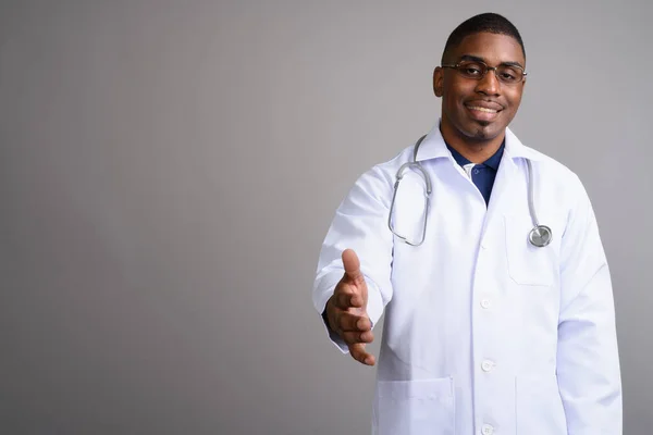 Young handsome African man doctor against gray background — Stock Photo, Image