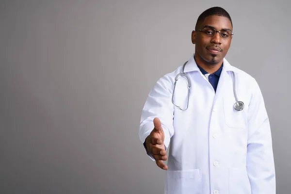 Joven guapo africano hombre médico contra gris fondo —  Fotos de Stock