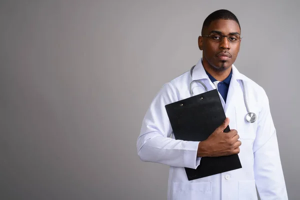 Junger schöner afrikanischer Arzt vor grauem Hintergrund — Stockfoto