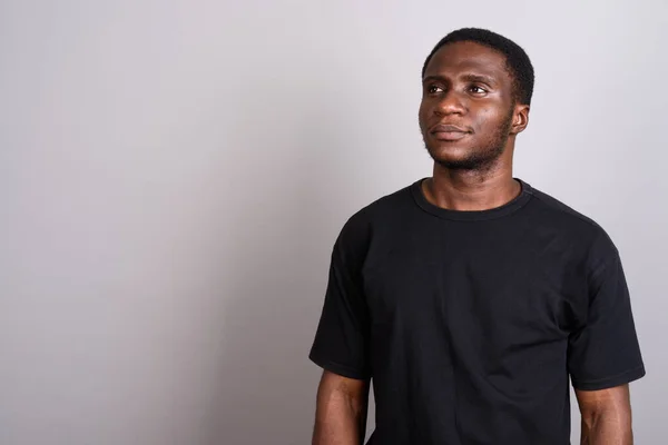 Afryki młody człowiek sobie czarną koszulę szarym tle — Zdjęcie stockowe