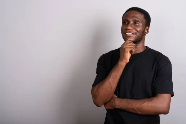 Young African man wearing black shirt against gray background