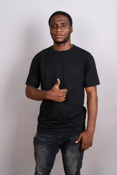 Young African man wearing black shirt against gray background — Stock Photo, Image