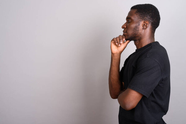 Studio shot of young African man wearing black shirt against gray background