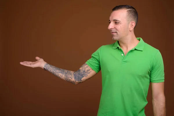 Man wearing green shirt against brown background — Stock Photo, Image