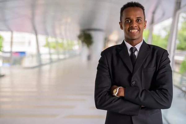 Portret van succesvolle jonge Afrikaanse zakenman lachend buiten met gekruiste armen — Stockfoto