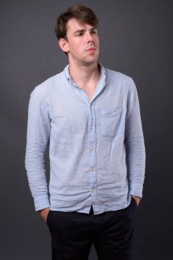 Genç ve yakışıklı adamın gri arka planda çekimleri.