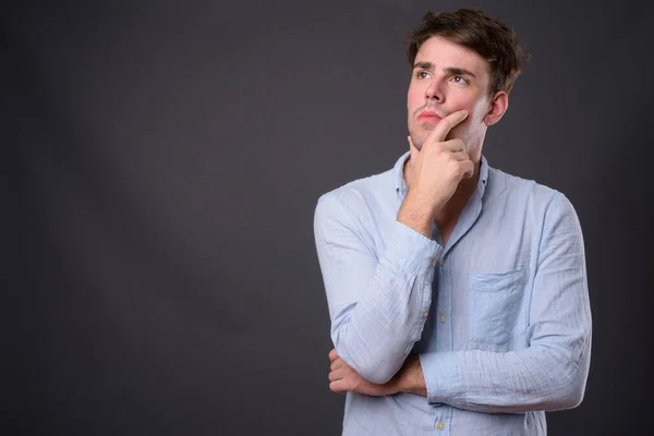 Studio shot van jonge knappe man tegen grijze achtergrond — Stockfoto