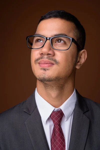 Jeune homme d'affaires asiatique multi-ethnique sur fond brun — Photo