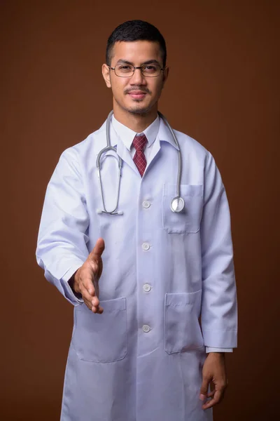 Jovem multi-étnico asiático homem médico contra fundo marrom — Fotografia de Stock
