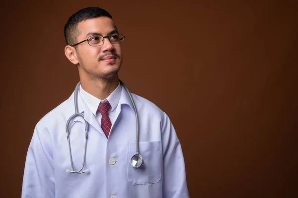 Joven multi-étnico asiático hombre médico contra fondo marrón — Foto de Stock