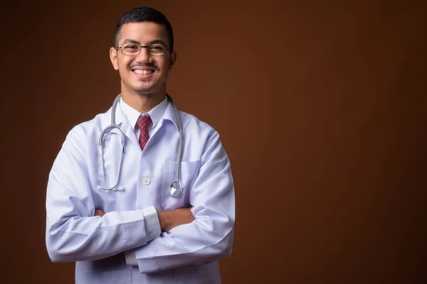 Joven multi-étnico asiático hombre médico contra fondo marrón —  Fotos de Stock