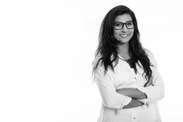 Studio shot of young happy Persian woman smiling while wearing eyeglasses with arms crossed — Stock Photo, Image