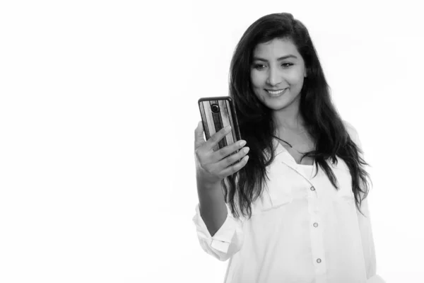 Studio shot of young happy Persian woman smiling while using mobile phone — ストック写真
