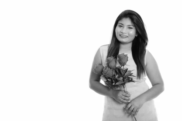 Studioaufnahme junger glücklicher, fetter persischer Teenager, der lächelnd rote Rosen in der Hand hält — Stockfoto
