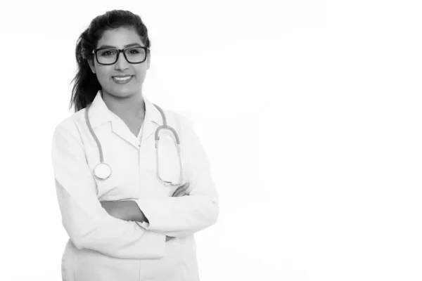 Studioaufnahme einer jungen glücklichen persischen Ärztin, die lächelnd eine Brille mit verschränkten Armen trägt — Stockfoto