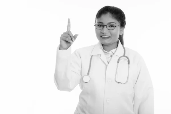 Estúdio tiro de jovem feliz gordura persa mulher médico sorrindo enquanto apontando o dedo para cima — Fotografia de Stock