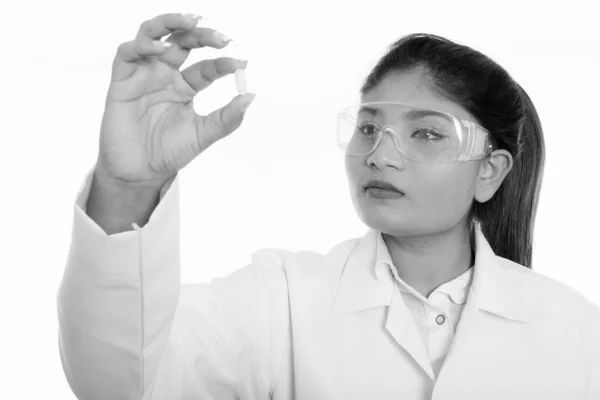 Närbild av ung fet persisk kvinna läkare tittar på vitamin tablett samtidigt bär skyddsglasögon — Stockfoto