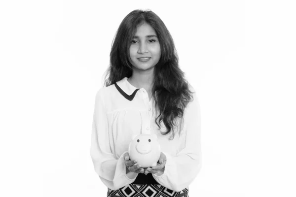 Studio shot of young happy Persian businesswoman smiling while holding piggy bank — ストック写真