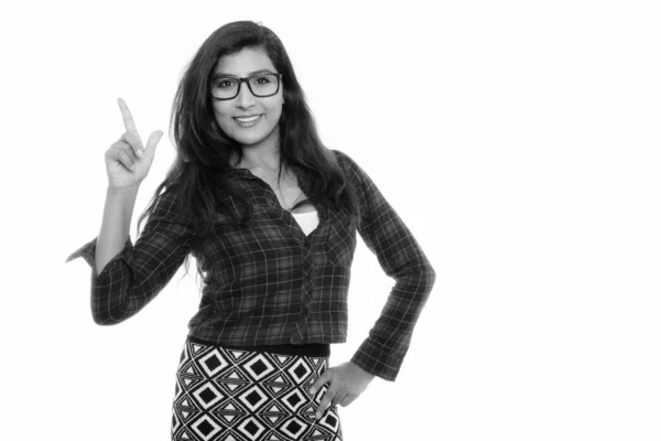 Studio shot of young happy Persian woman smiling while pointing finger up with eyeglasses isolated — ストック写真