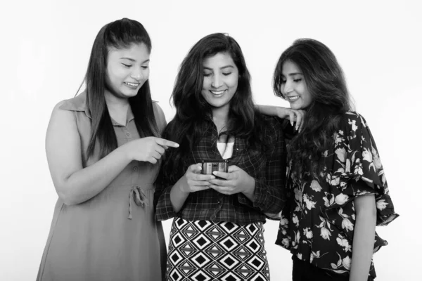 Estudio de tres felices jóvenes amigas persas sonriendo mientras usan un teléfono móvil juntas —  Fotos de Stock