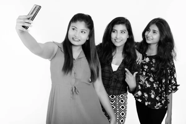 Studio skott av tre glada unga persiska kvinna vänner ler samtidigt ta selfie bild med mobiltelefon tillsammans — Stockfoto