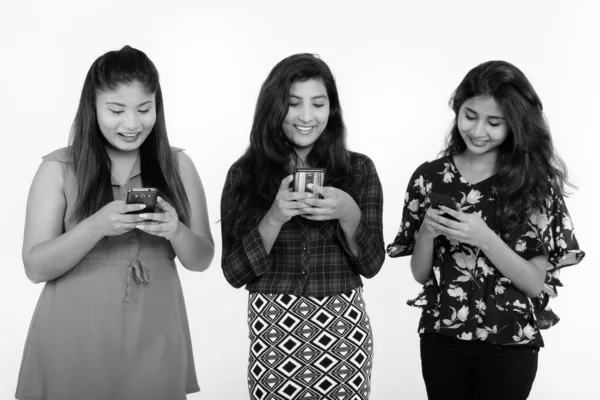 Estúdio tiro de três felizes jovens persas amigos mulher sorrindo ao usar telefones celulares juntos — Fotografia de Stock