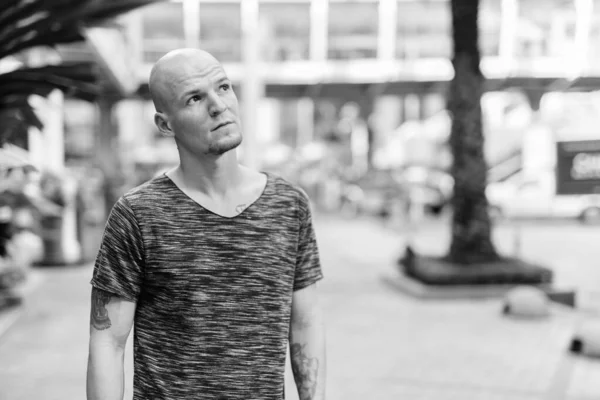 Young handsome bald man thinking outside the mall — Stock Photo, Image