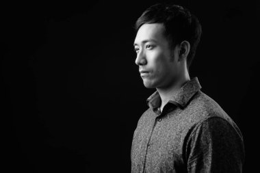 Genç yakışıklı Asyalı işadamı siyah arka plana karşı